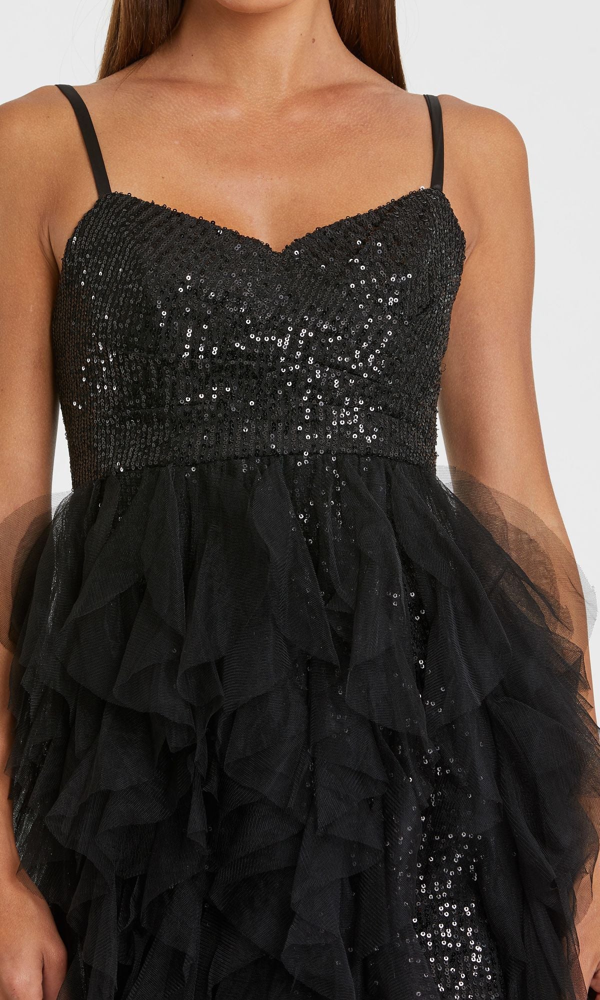 A woman wears the Mac Duggal 27119 Overskirt Mini Sequin Prom Dress, featuring sequin embellishments on the bodice and layered tulle ruffles on the skirt.